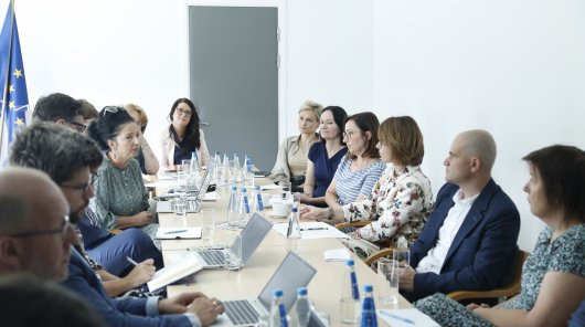 Zdjęcie przedstawia osoby uczestniczące w spotkaniu prezesa UODO z inspektorami ochrony danych w sądach. Uczestnicy spotkania siedzą po obu stronach stołu. 